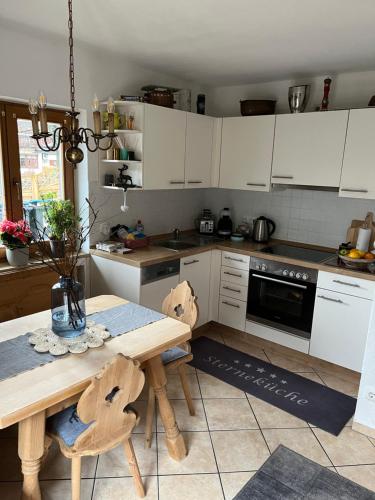 a kitchen with white cabinets and a wooden table at Engelsherz in Mittenwald