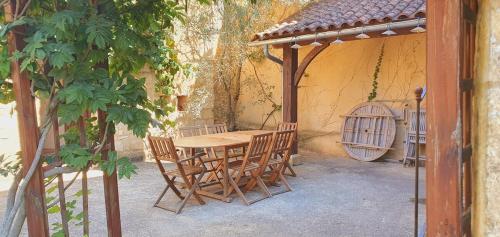 una mesa de madera y sillas bajo una pérgola en Maison Domme Dordogne en Domme