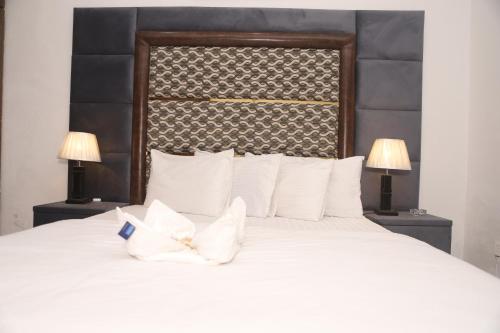 una camera da letto con un grande letto bianco con due lampade di Hotel Royal Comfort a Lahore