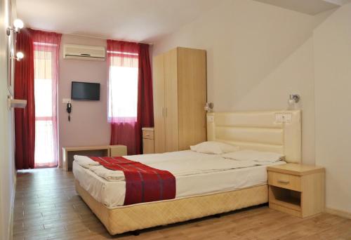 a bedroom with a large bed with red curtains at Rilena Hotel in Kiten