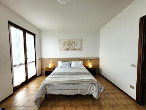 a bedroom with a large bed with two windows at Panorama Verde Lago - Mountain Lake Iseo Hospitality in Bossico