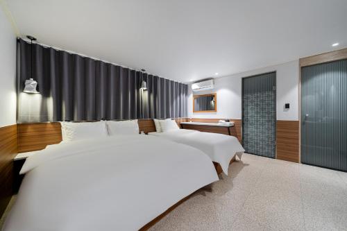 a bedroom with two beds and a bathroom at Jamsil Noblestay Hotel in Seoul