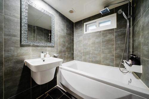 a bathroom with a sink and a bath tub and a mirror at Jamsil Noblestay Hotel in Seoul