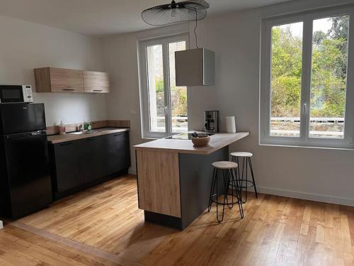una cucina con frigorifero nero e bancone con sgabelli di Appartement centre - Avranches ad Avranches