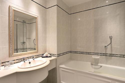 a white bathroom with a sink and a bath tub at Macdonald Leeming House in Watermillock
