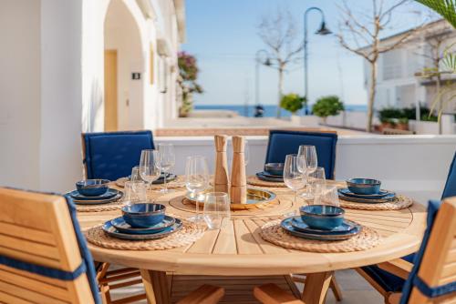 a wooden table with plates and glasses on it at La Familia Beach House La Cala in La Cala de Mijas