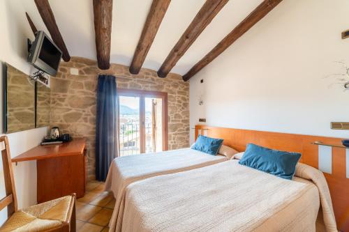 1 dormitorio con 2 camas, TV y ventana en HOTEL EL CASTELL, en Valderrobres