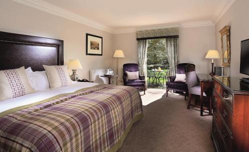 a hotel room with a bed and chairs and a television at Macdonald Leeming House in Watermillock