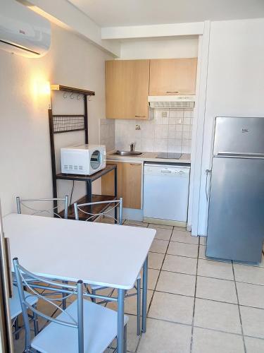 Il comprend une cuisine équipée d'une table blanche et d'un réfrigérateur. dans l'établissement Résidence Graziella Studio 624, à Juan-les-Pins