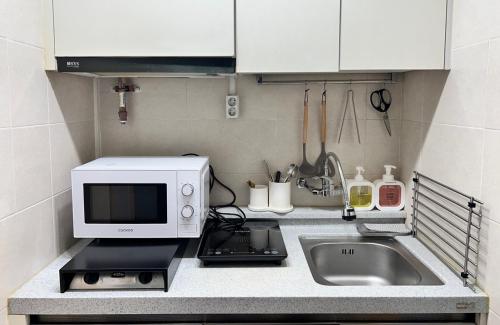 a kitchen counter with a microwave and a sink at Masil in Seoul