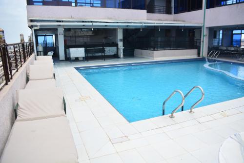 ein großer Pool mit zwei Bänken neben einem Gebäude in der Unterkunft BRIMAK HOTEL in Embakasi