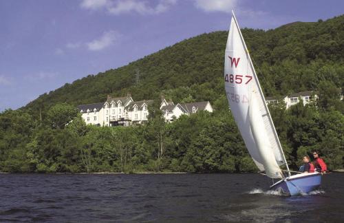 two people on a sail boat in the water at Macdonald Leeming House in Watermillock