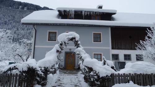 a snow covered house with a yellow door at Ferienwohnung Aigner im Salzburger Lungau in Muhr