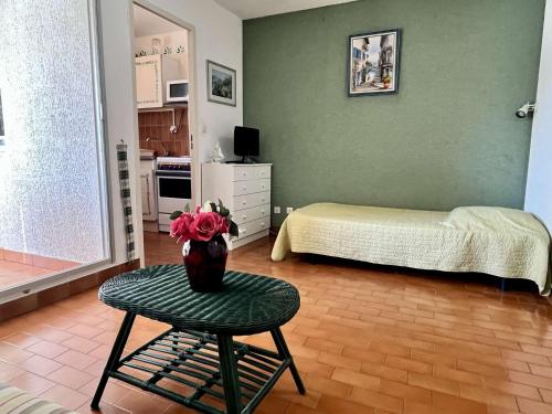 - une chambre avec un lit et une table avec un vase dans l'établissement Studio à Argelès-sur-Mer, 400m de la plage et proche commerces, loggia, animaux bienvenus, ménage inclus - FR-1-225-548, à Argelès-sur-Mer