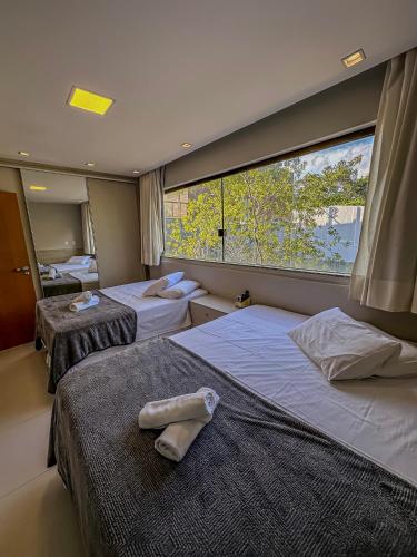 two beds in a room with a large window at Imbassaí Apartments in Imbassai