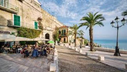 a group of people sitting at tables on a sidewalk near the ocean at Casa Cele centro città vista mare in Ventimiglia