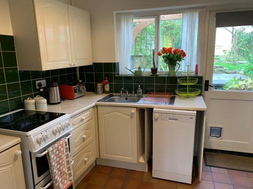 a kitchen with a sink and a stove top oven at Bell Cottage in Bridport