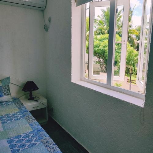 a bedroom with a bed and an open window at White Sand Cabana in Flic-en-Flac