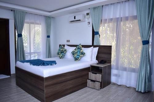 a bedroom with a large bed with blue curtains at Makaazi Nyali in Mombasa