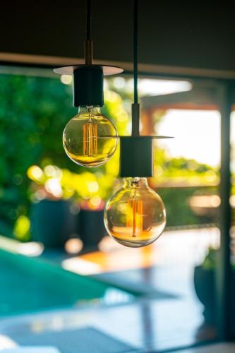 two glass lights are hanging from a table at Maison Gaia Seychelles, unobstructed views over the ocean and into the sunset in Glacis