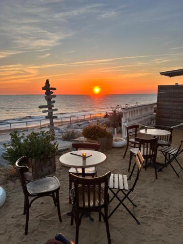 einen Sonnenuntergang am Strand mit Tischen und Stühlen in der Unterkunft Appartement 2 pièces tout équipé à 100 m de la plage avec place de parking in Saint-Hilaire-de-Riez