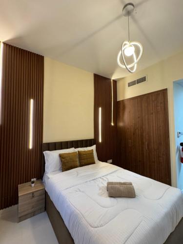 Un dormitorio con una gran cama blanca y una lámpara de araña. en RksHome Studio Apartment Baniyas Metro Exit 2, en Dubái
