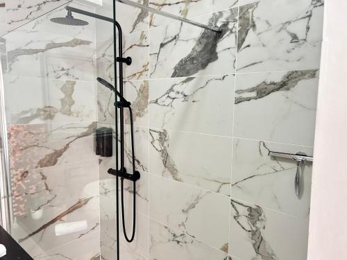 y baño con ducha y azulejos de mármol. en Monaco Cap d’ail Studio & jardin, en Cap d'Ail