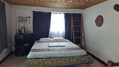 1 dormitorio con 1 cama con escalera y ventana en Bugoy Bikers Hostel en Cebú