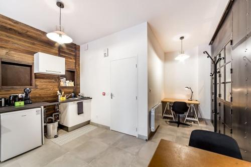 - une cuisine avec des placards blancs et un mur en bois dans l'établissement Superbe studio style industriel à Charbonnière, à Charbonnières-les-Bains
