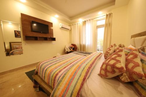 a bedroom with a bed and a television on the wall at Perfectstayz Value Hills near Laxman Jhula in Rishīkesh