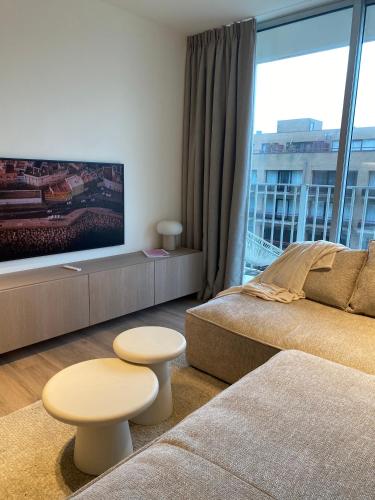 a living room with a couch and a large window at Luxe appartement `t Sant Nieuwpoort Bad in Nieuwpoort