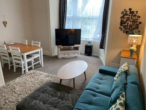 a living room with a blue couch and a table at Spacious 1 Bedroom Apartment near Seafront in Penzance