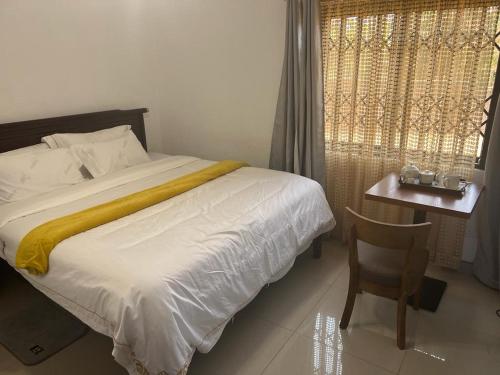 um quarto com uma cama, uma cadeira e uma janela em PGD Homes & Lodges em Blantyre