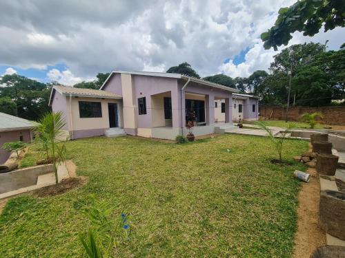 una casa con un patio de hierba delante de ella en PGD Homes & Lodges, en Blantyre