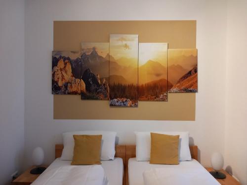 two beds in a room with three paintings on the wall at Hotel Karolinger in Düsseldorf