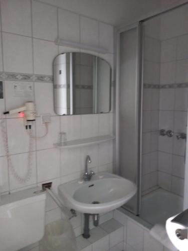 a bathroom with a sink and a shower and a mirror at Hotel Karolinger in Düsseldorf