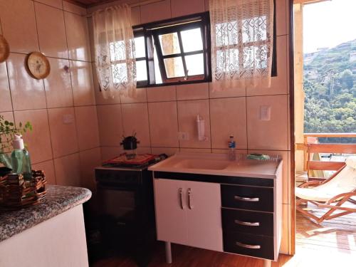 una pequeña cocina con fregadero y ventana en Casa de Boneca, en Campos do Jordão