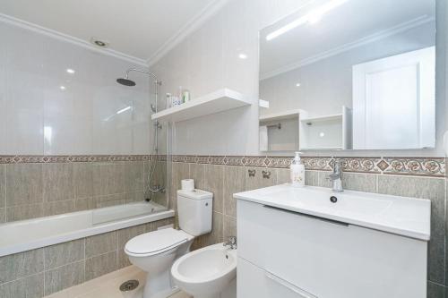 a bathroom with a toilet and a sink and a mirror at Moderno piso en el corazón de Baiona by CABANA Rentals in Baiona