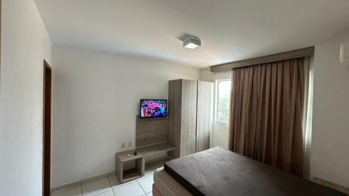 カルダス・ノバスにあるPRIVÉ RIVIERA PARK Apto Hotelのベッドと壁にテレビが掛かった寝室