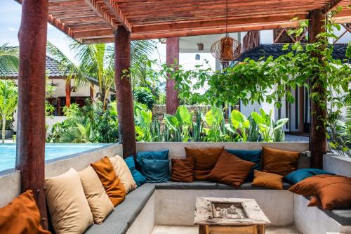 a couch sitting under a pergola next to a pool at Baobab Bungalows in Jambiani