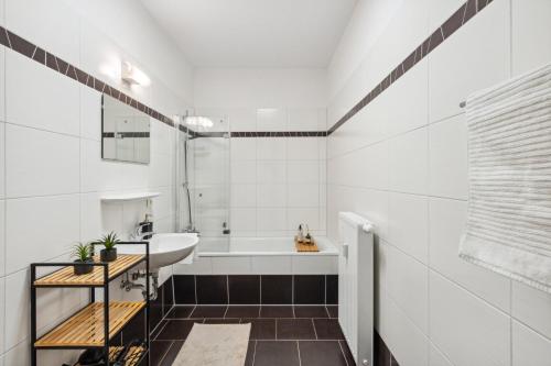 Baño blanco con lavabo y bañera en Homespace - Magdeburg - Gemütliches Apartment mit Balkon en Magdeburgo