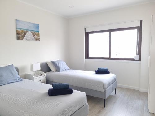 Habitación blanca con 2 camas y ventana en Beach Apartment w/Ocean view en Costa da Caparica