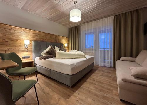 ラートシュタットにあるNatur & Familienhotel Der Stieglerhofのベッドルーム1室(ベッド1台、ソファ、椅子付)