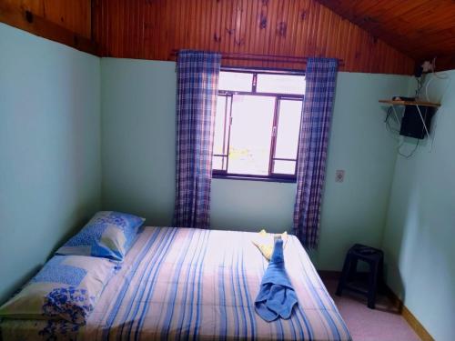 Schlafzimmer mit einem Bett und einem Fenster mit Vorhängen in der Unterkunft POUSADA DO BAR- BUDO in Itatiaia