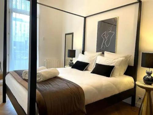um quarto com uma cama grande com lençóis brancos e almofadas em E Fauvette appartement de standing avec terrasse em Épernay