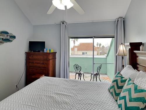a bedroom with a bed with two chairs and a window at Cozy Coastal Repose in Padre Island