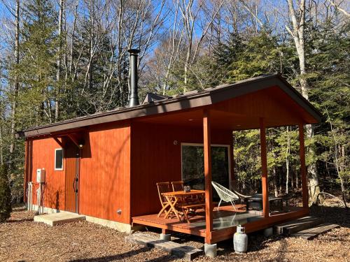 una cabaña en el bosque con mesa y sillas en 八ケ岳リゾートSILVI en Hara