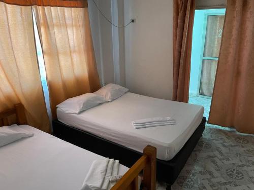 Duas camas num pequeno quarto com uma janela em Hotel CAB DE TOLU em Tolú