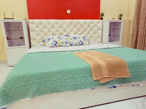 Kigali Peace vill في كيغالي: غرفة نوم بسرير كبير مع بطانية خضراء