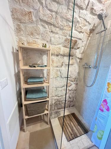 a bathroom with a walkin shower and a shelf with towels at VILLA DOMINIQUE relax a pochi kilometri dal mare in Carovigno